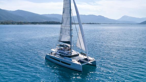 The white catamaran Kimata sails on the blue sea near the Cyclades.