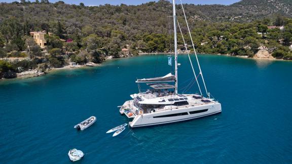 The catamaran Kimata anchored in a secluded bay with emerald green waters.