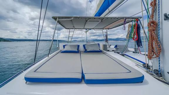 Luna 49 Blue katamaranın üst güvertesinde yer alan minderli yataklar, tenteyle gölgelenmiş rahat bir güneşlenme alanı su