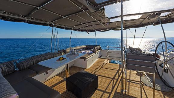 Cozy lounge deck of the Lagoon 560 S2 Meliti with seating and a table under a shaded canopy