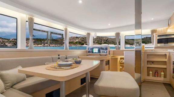 The Lagoon 42 catamaran offers an inviting dining area with panoramic windows and coastal views.