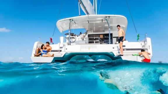 Guests jump into crystal-clear waters from the Lagoon 42 catamaran, enjoying a perfect day in the sun.