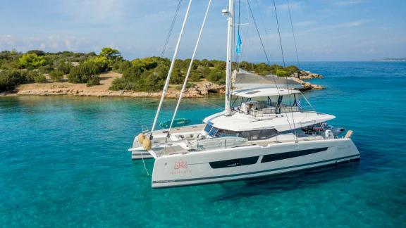 Catamaran on clear turquoise waters near a green coastline