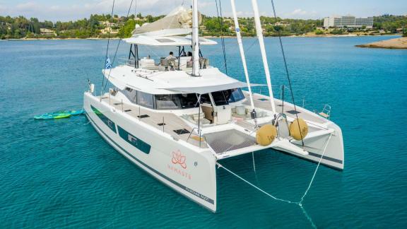 Catamaran Namaste, peacefully anchored on turquoise waters near green hills