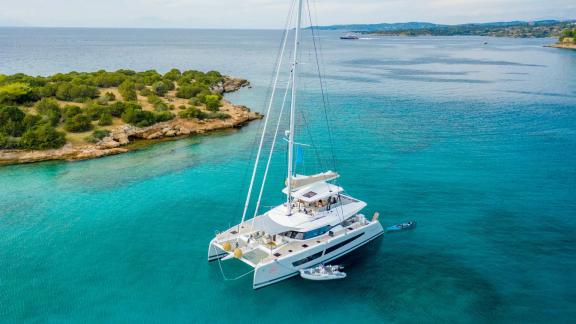 Catamaran anchored in a calm bay with green-covered coastline