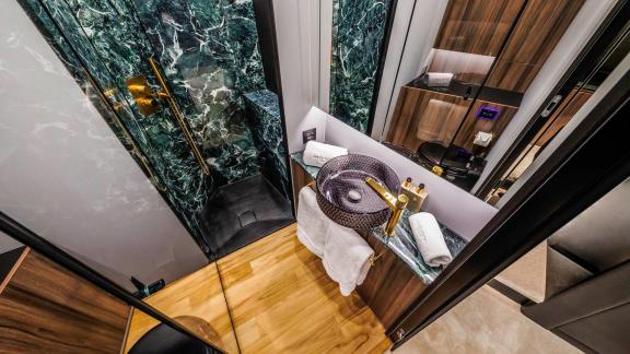 Dark green marble and a designer sink elevate the style of this charter yacht’s bathroom.