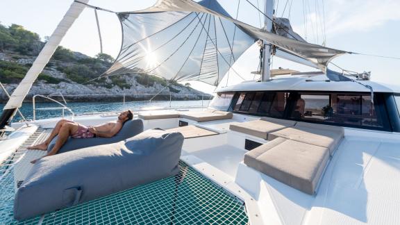 A man relaxes on a comfortable lounge on the net of the catamaran Pi 2 in Athens.