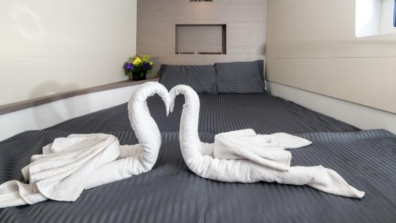 Unter den Katamaran Charter Optionen in Lefkada zeigt Premium Kabine mit Bett und dekorativen Handtüchern.