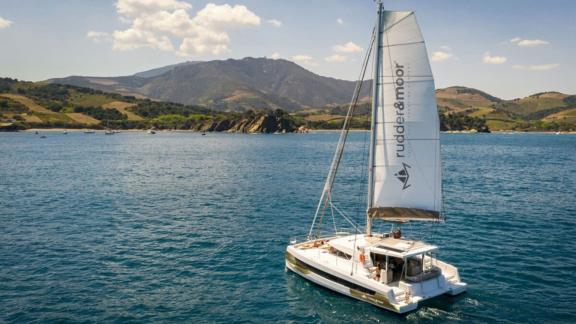 The catamaran Bali 4.2 Sah Mat sails calmly on turquoise waters off the scenic coast of Fethiye, Turkey.