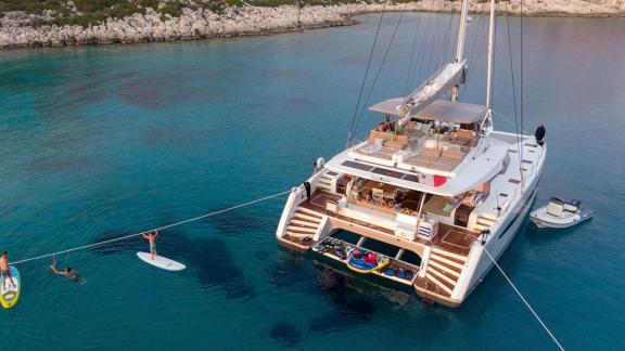 The luxurious catamaran Serenissima anchored in clear turquoise waters near the coast of Athens.