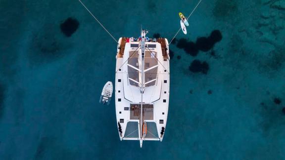 The Serenissima catamaran photographed from above, floating in crystal-clear waters.