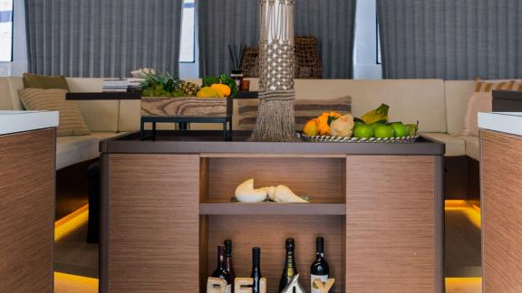 A stylish salon area on a catamaran featuring decorative fruits, wine bottles, and a relaxed ambiance.