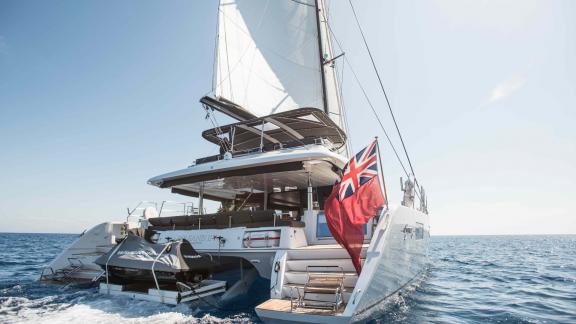 Catamaran Soleanis II from the rear, with a raised red flag on the open sea