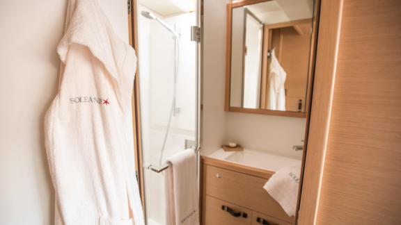 Bathroom on Soleanis II with shower, mirror, and hanging bathrobe with yacht logo