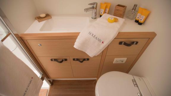 Compact bathroom on Soleanis II with sink, towel, and provided toiletries