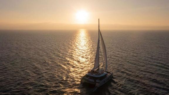 The catamaran Spice of Life sails in golden light off the coast of Athens.