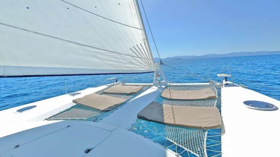 Comfortable sunbeds on the foredeck of the catamaran Zorba, perfect for relaxing moments at sea.