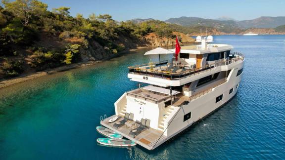 Die Yacht Çınar Yıldızı bietet ein luxuriöses Erlebnis in einer ruhigen Bucht, umgeben von türkisfarbenem Wasser und Grü