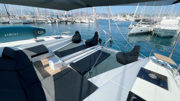 Clara katamaranının geniş ön güvertesi, Marmaris'teki yat limanına bakan rahat şezlonglar ve oturma minderleri sunuyor.