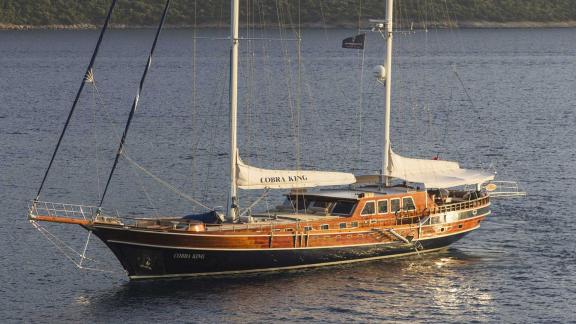 Elegante Gulet Cobra King in einer ruhigen Bucht von Bodrum, Türkei vor Anker, umgeben von grünen Hügeln.