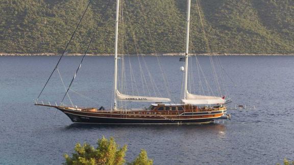 Die Gulet Cobra King vor Anker in einer geschützten Bucht in Bodrum, umgeben von grünen Hügeln.