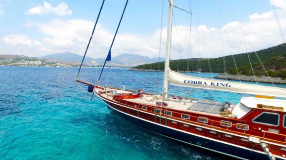 Die elegante Gulet Cobra King im türkisfarbenen Wasser von Bodrum, umgeben von malerischen Hügeln.