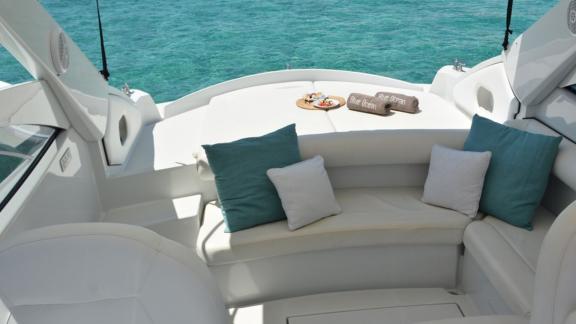 Cozy seating area on motor yacht Black Ball, decorated with pillows and a sea view.