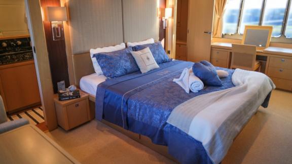 Double bed with blue linens in a bright bedroom on a yacht