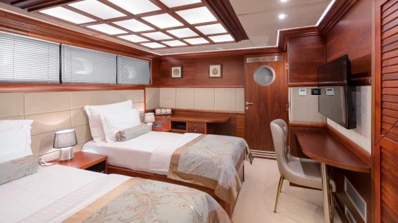 Роскошная спальня с двумя кроватями, столом и телевизором на яхте Lady Gita.