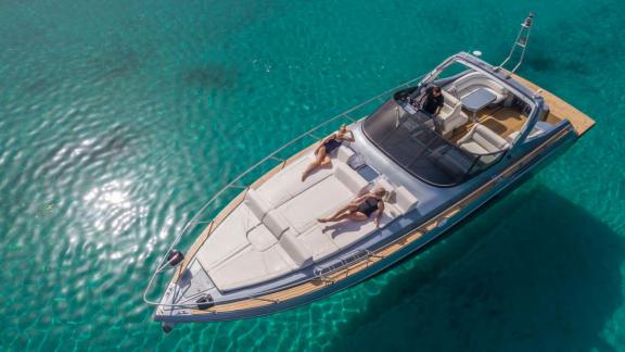 Guests are sunbathing on the foredeck of Este yacht, enjoying the clear waters of Mykonos.