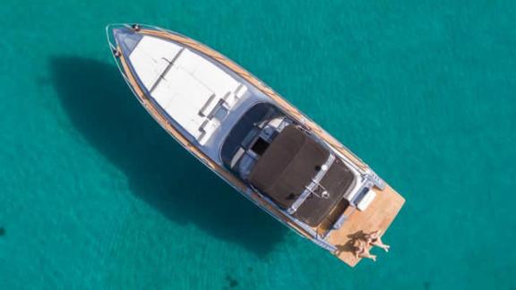 Este motoryat, Mykonos açıklarında turkuaz deniz üzerinde tüm şıklığıyla görülüyor.
