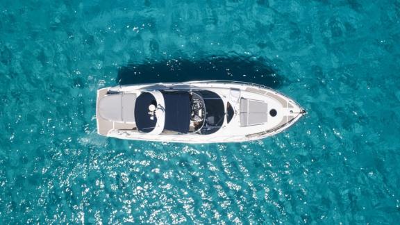 Die Com Tu Motoryacht liegt vor Anker im türkisfarbenen Wasser bei Ibiza.