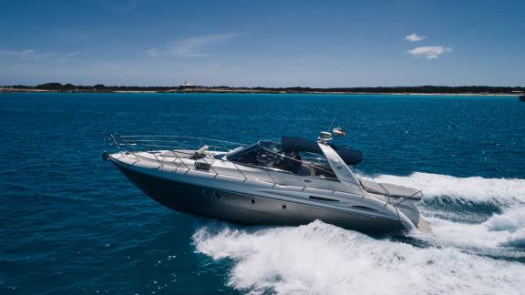 Die Motoryacht Com Tu fährt mit hoher Geschwindigkeit vor der Küste Ibizas.