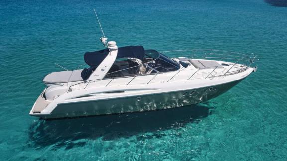 Die Motoryacht Com Tu liegt im klaren Wasser vor der Küste von Ibiza.