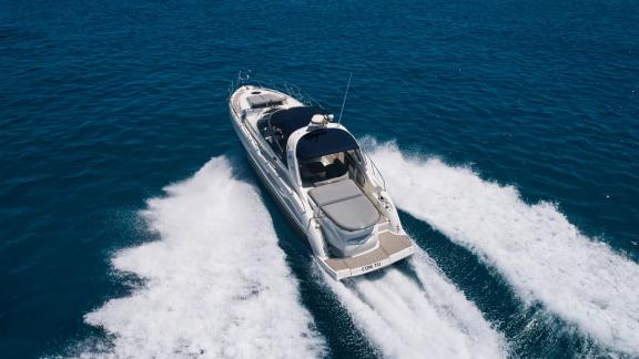 Die Motoryacht Com Tu fährt rasant vor Ibiza Rückansicht auf See.