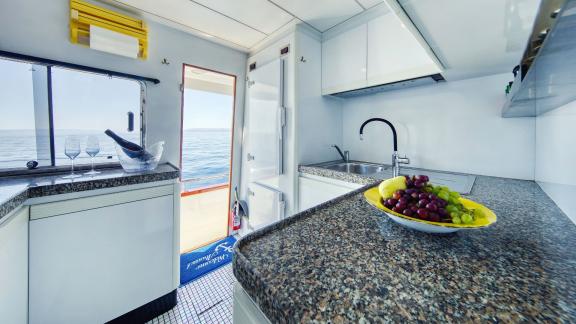 The stylish kitchen of motor yacht Custom Blanka features a fruit bowl and a sea view.