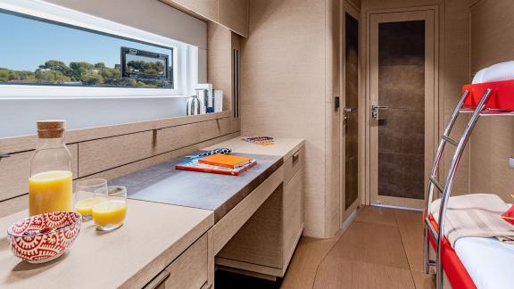 Functional workspace on the Catamaran Daiquiri featuring natural light, a panoramic window, and an adjacent bunk bed for