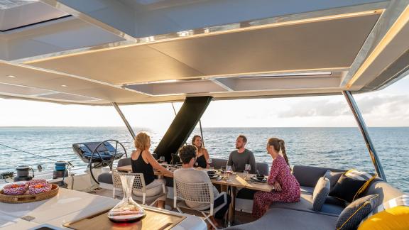 Guests enjoying a cozy dinner onboard the Catamaran Daiquiri as the sun sets over the sea.