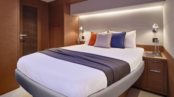 The elegant cabin on the Catamaran Daiquiri features a comfortable double bed, modern wood accents, and warm lighting.