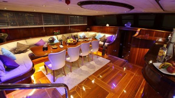 The stylish saloon of the gulet Dear Lila by night offers an elegant dining and lounge area.