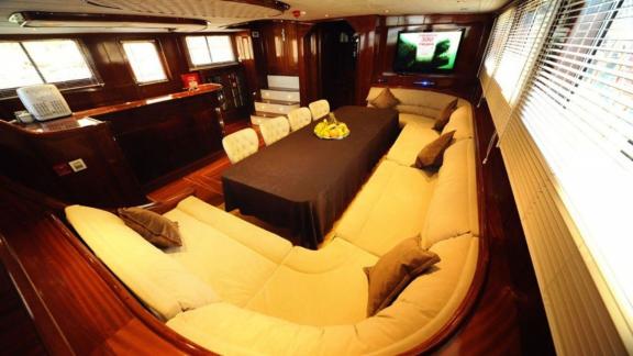 The spacious saloon of the gulet Dear Lila offers comfortable seating and a large dining table.