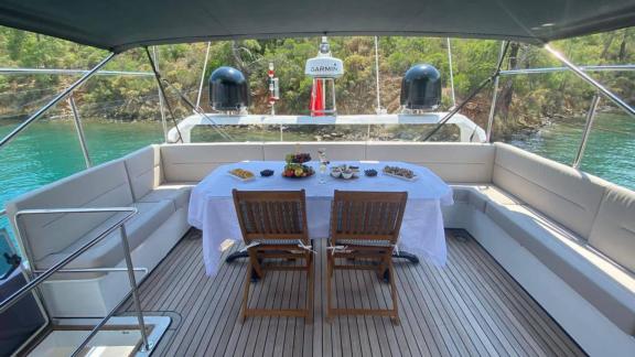 The upper deck of motor yacht Serpil D features a table with fruits and drinks.