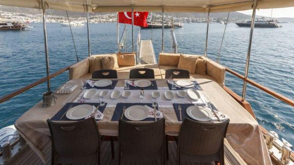 Stilvoll gedeckter Esstisch auf der Heckterrasse der Gulet Okay 2 mit Blick auf das Meer und die türkische Flagge im Hin