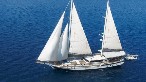 Gulet Derya Deniz mit 5 Kabinen, weißen Segeln und edlem Holzdeck, segelt auf blauem Meer in Marmaris.