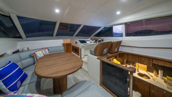 The salon of Karan motor yacht includes a dining table, seating area, and a fully equipped kitchen.