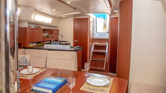 The saloon of the Beau Gosse sailing yacht offers a comfortable living area with a dining table and galley.