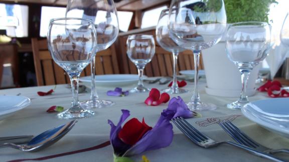 Close-up of a stylish table setting with glasses and petals on the Gulet Life is Life.