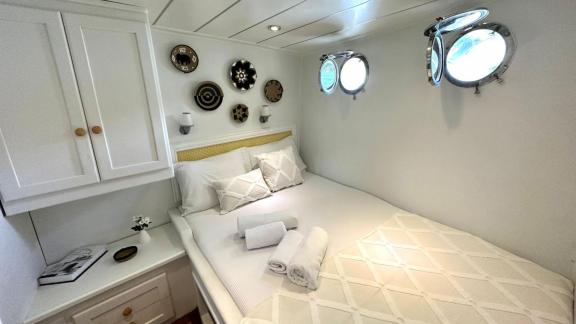 Tastefully decorated cabin with double bed, decorative wall plates, and portholes on Gulet Bohemian.