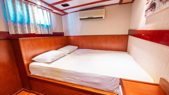 Guest cabin of Gulet Esperanza featuring a double bed, wood paneling, and an air conditioning unit above the bed.