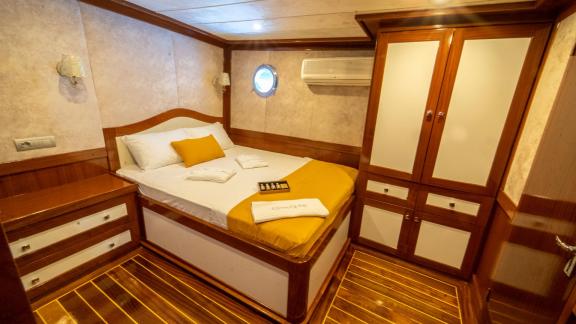 The comfortable cabin of the gulet Queen of RTT in Fethiye has a double bed, storage space and a porthole for a maritime